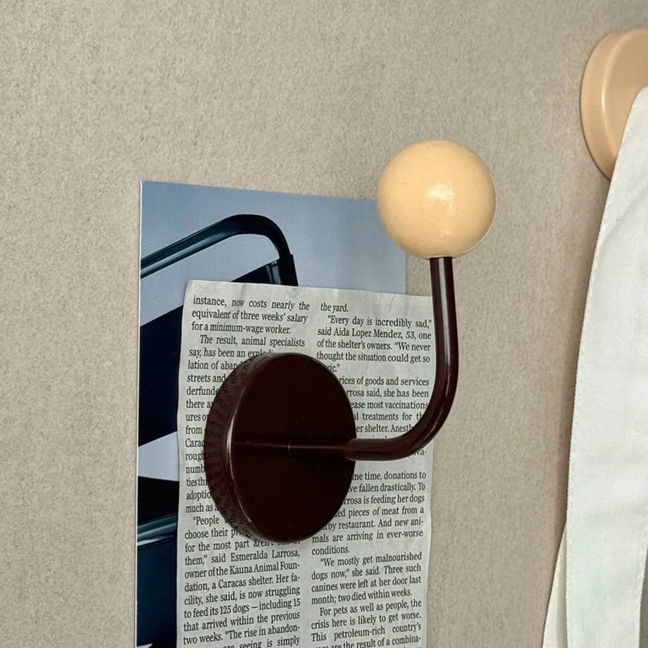 Cream & Brown Color Block Metal Hook holding a collage of papers on a wall, next to a white towel - RoomDen.