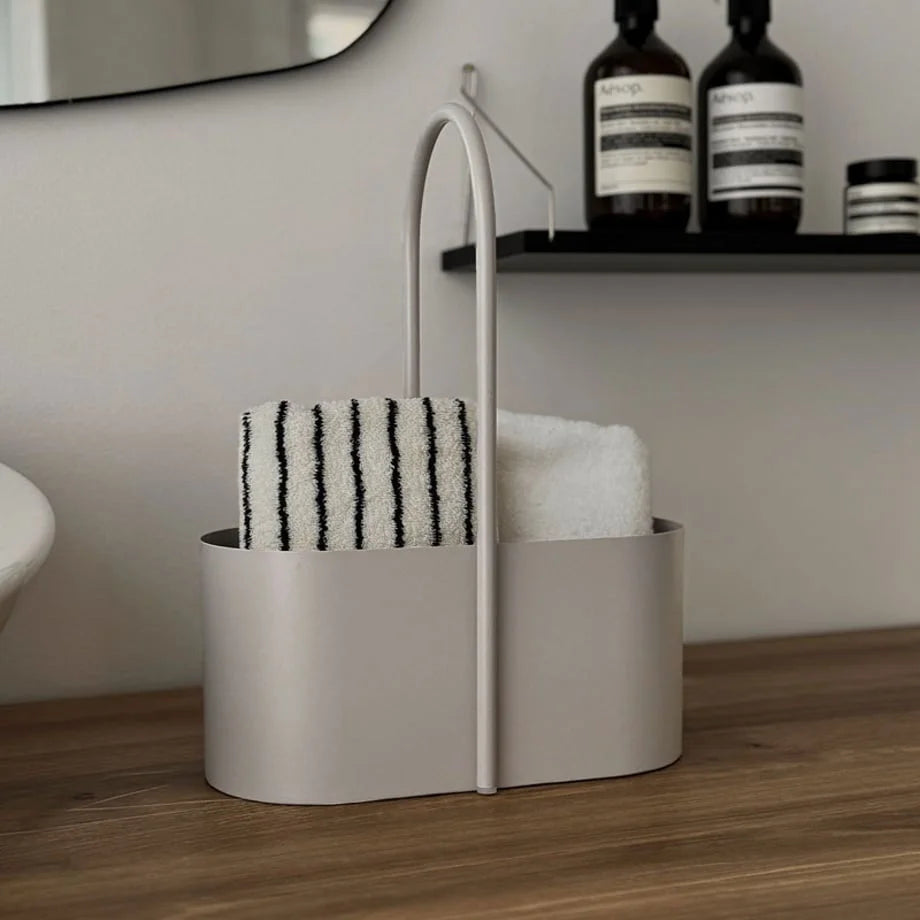 Front view of the beige metal organizer caddy filled with rolled towels in a bathroom setting. - RoomDen