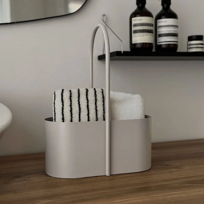 Front view of the beige metal organizer caddy filled with rolled towels in a bathroom setting. - RoomDen