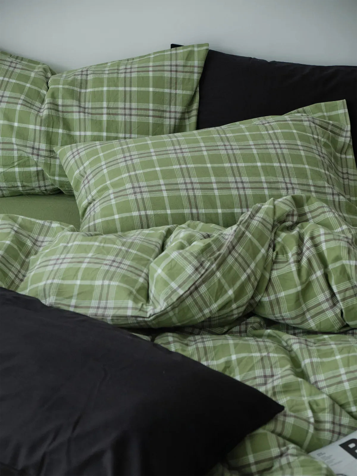 A detailed shot of the matcha green plaid pillowcases and duvet cover, highlighting the pattern and the soft, wrinkled texture of the fabric. - RoomDen