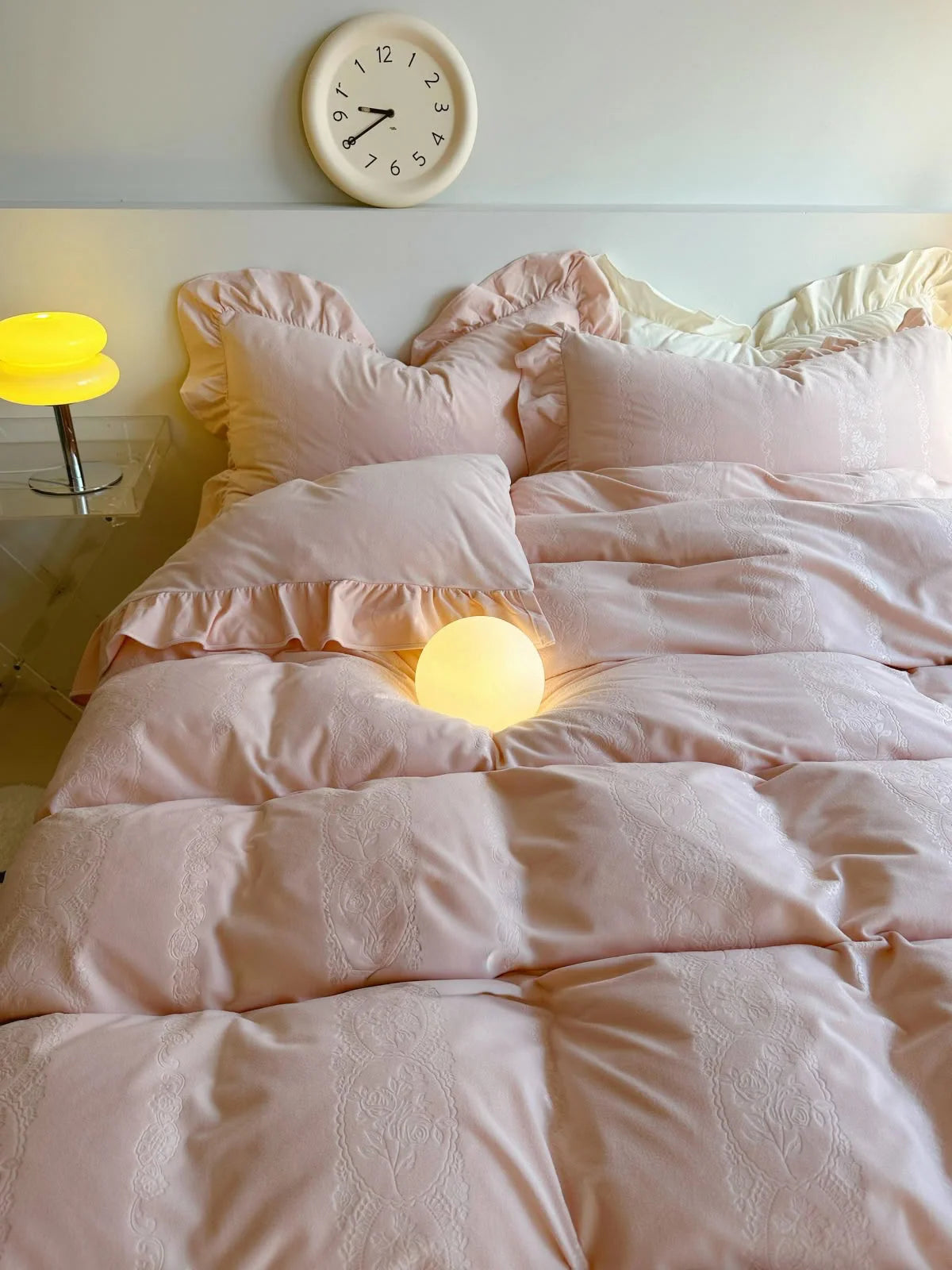 Headboard view of the Blush Pink Ruffled Velvet Bedding with a warm orb light. - RoomDen