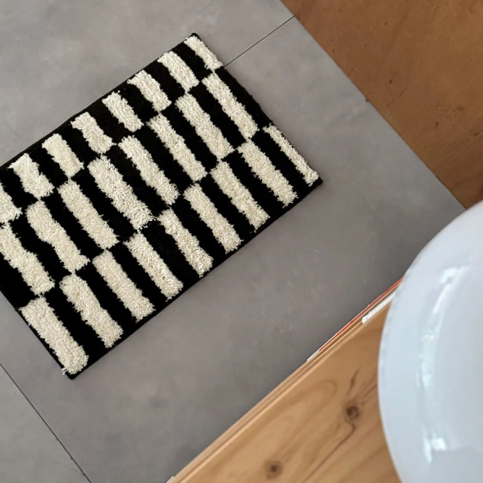 Top-down view of the rectangular black and white striped rug showing the broken stripe pattern - RoomDen