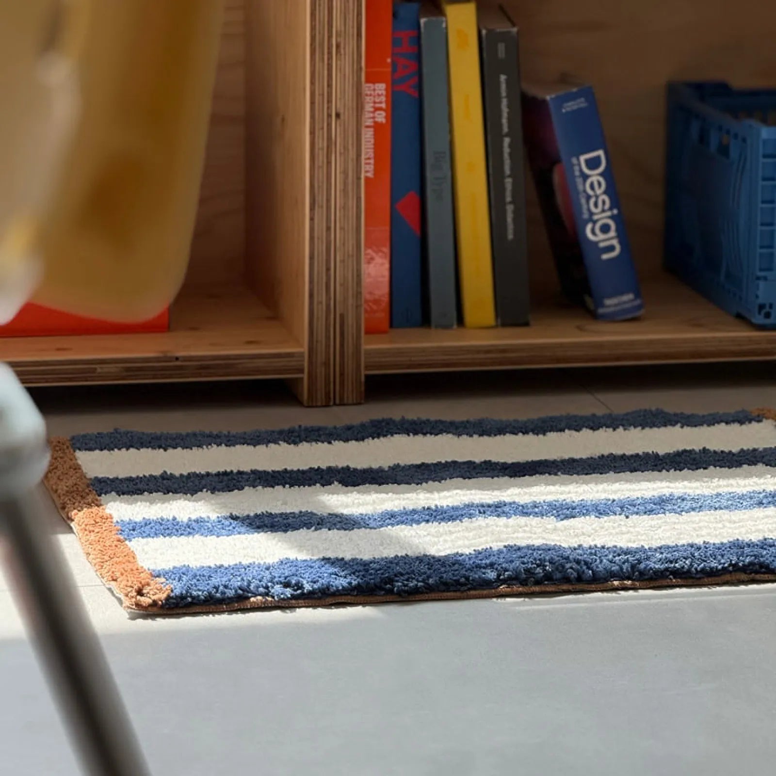 Striped rug in a room setting with blue crate and books - RoomDen