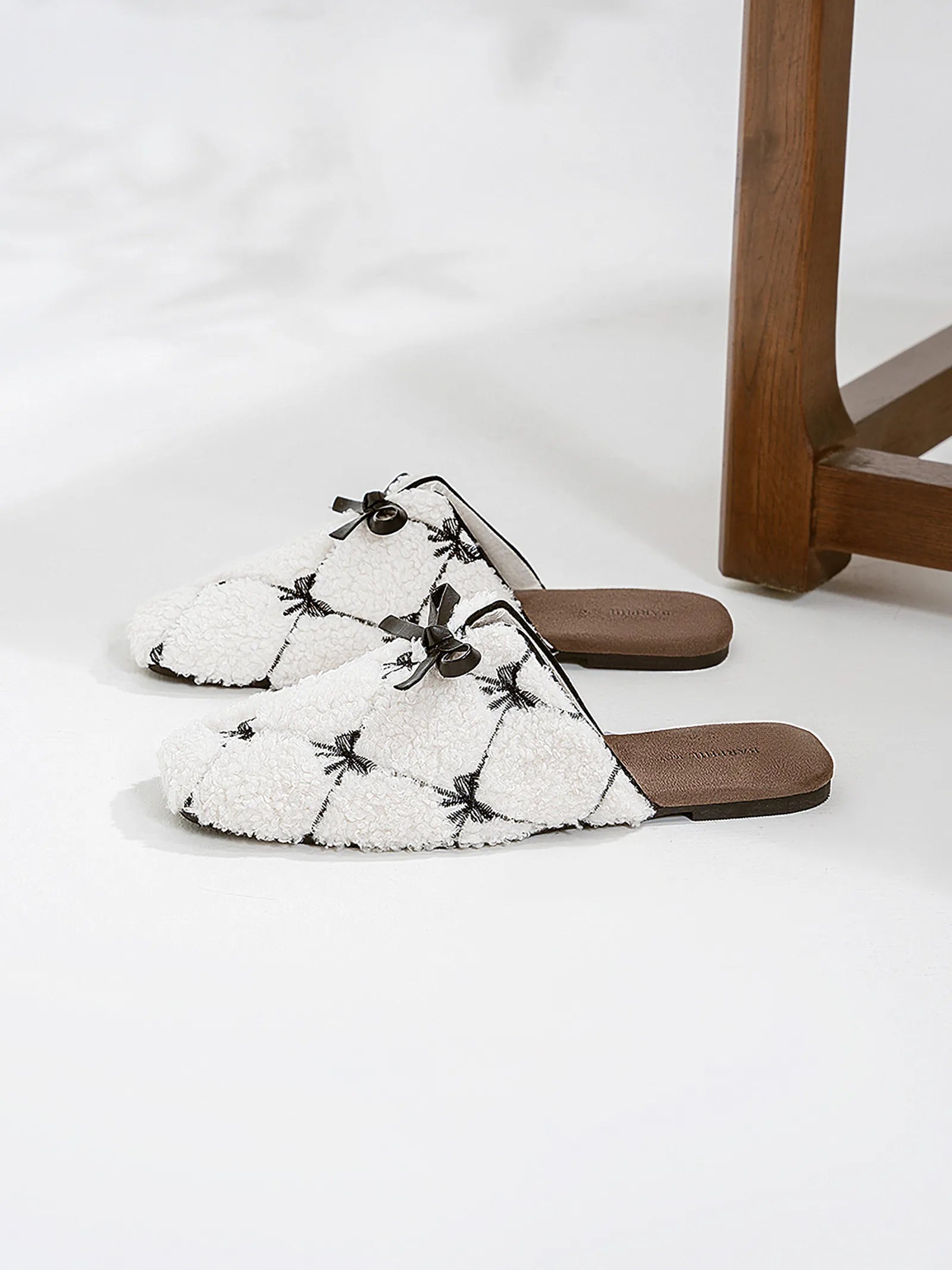 Pair of cute coquette style white sherpa slippers on white floor - RoomDen