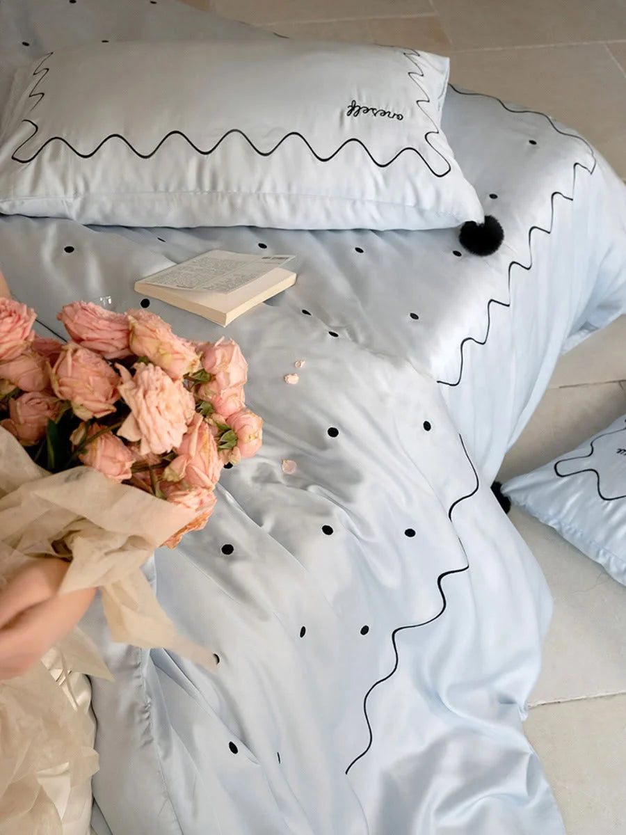 Overhead close-up of the Baby Blue & Black Tencel duvet cover with a bouquet of pink roses. - RoomDen