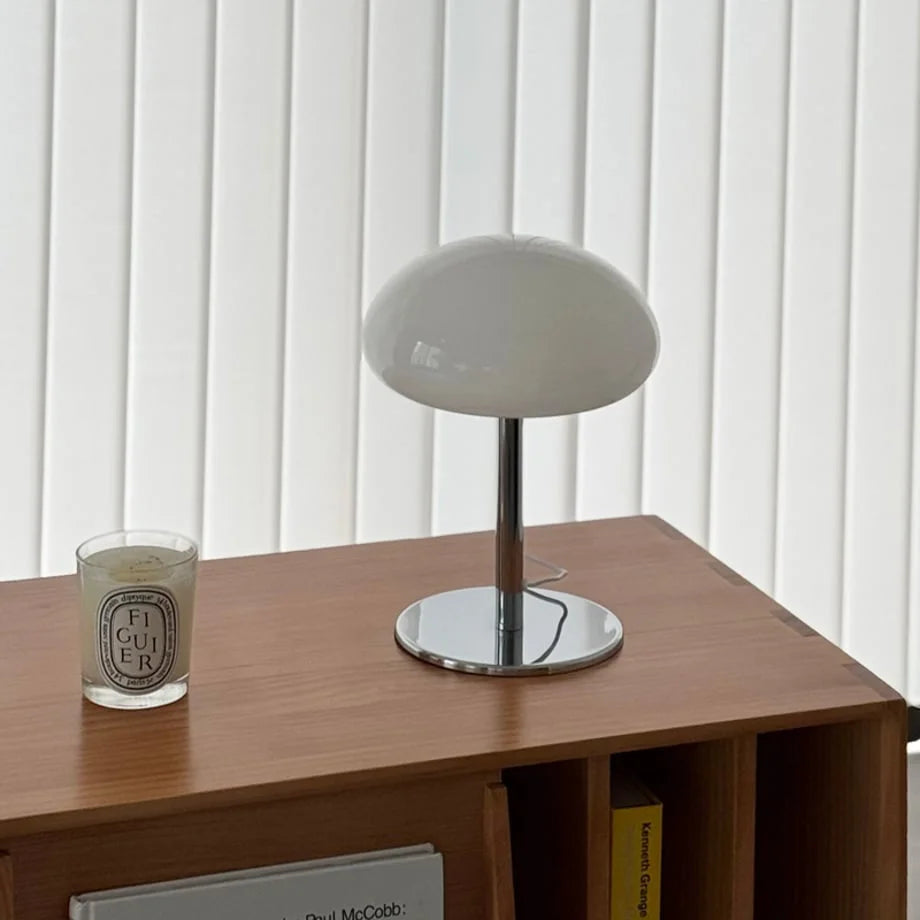 Close-up of the white mushroom table lamp next to a candle on a wooden surface - RoomDen.