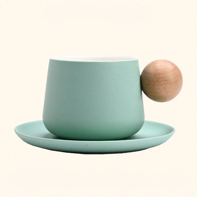 A studio shot of the Mint Green Frosted Ceramic Mug and Saucer Set with a wooden ball handle. - RoomDen