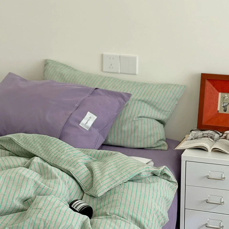 Close-up showing the soft texture of the Mint & Lavender striped duvet and the solid lavender pillowcase - RoomDen.