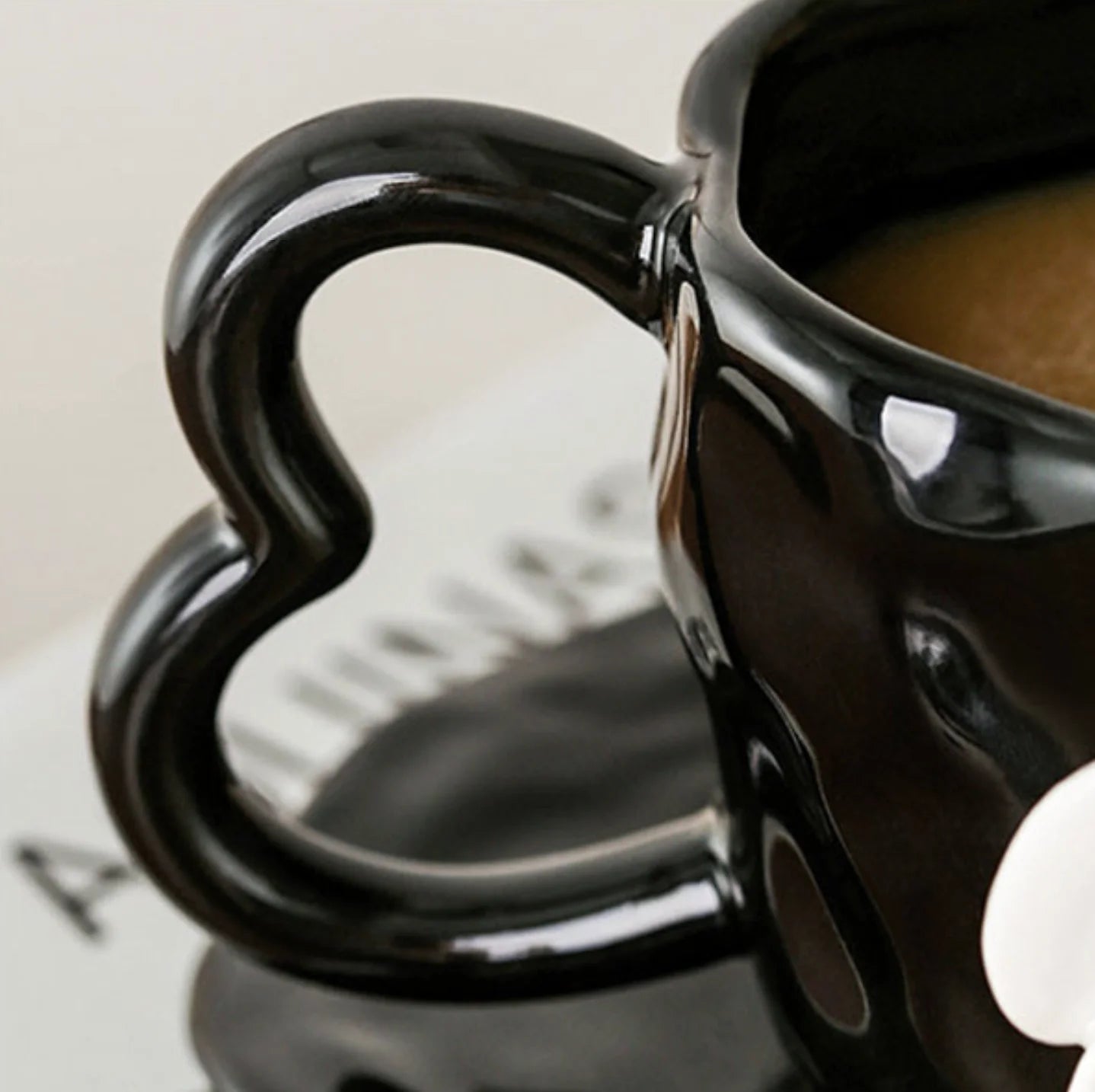 Close-up of the heart-shaped handle on the black ceramic mug - RoomDen