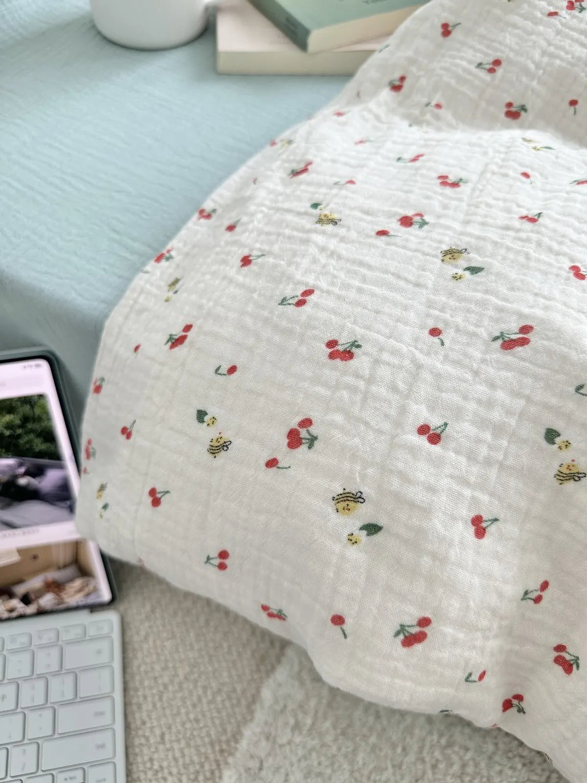 Detail shot of the cherry and bee pattern on the textured cream fabric, showing the embroidery-like print quality. RoomDen.