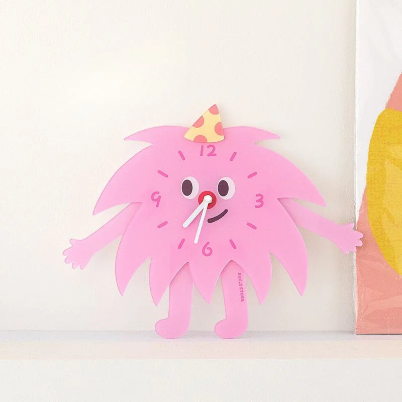 The pink monster table clock standing on a white shelf, adding a pop of color to a minimalist room.