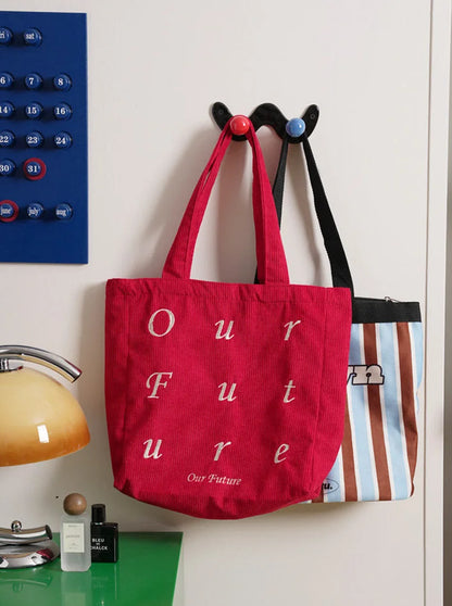A red tote bag and a striped bag hanging from a black wavy wall hook with red and blue balls.