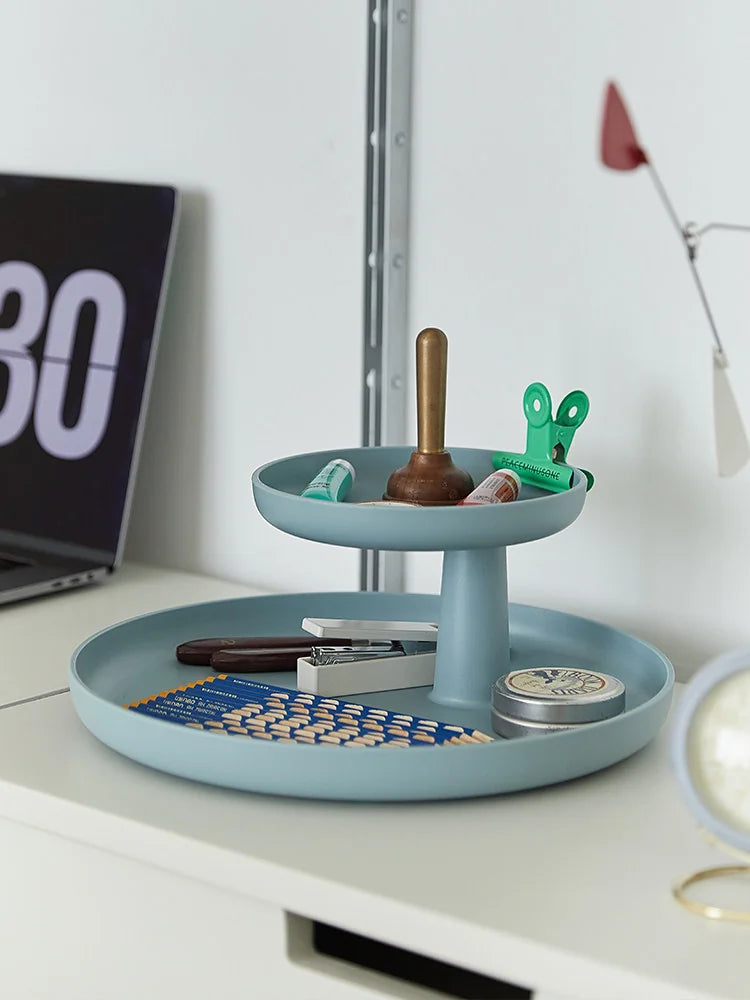 Dusty blue two-tier organizer tray with stationery and office supplies on a desk — RoomDen