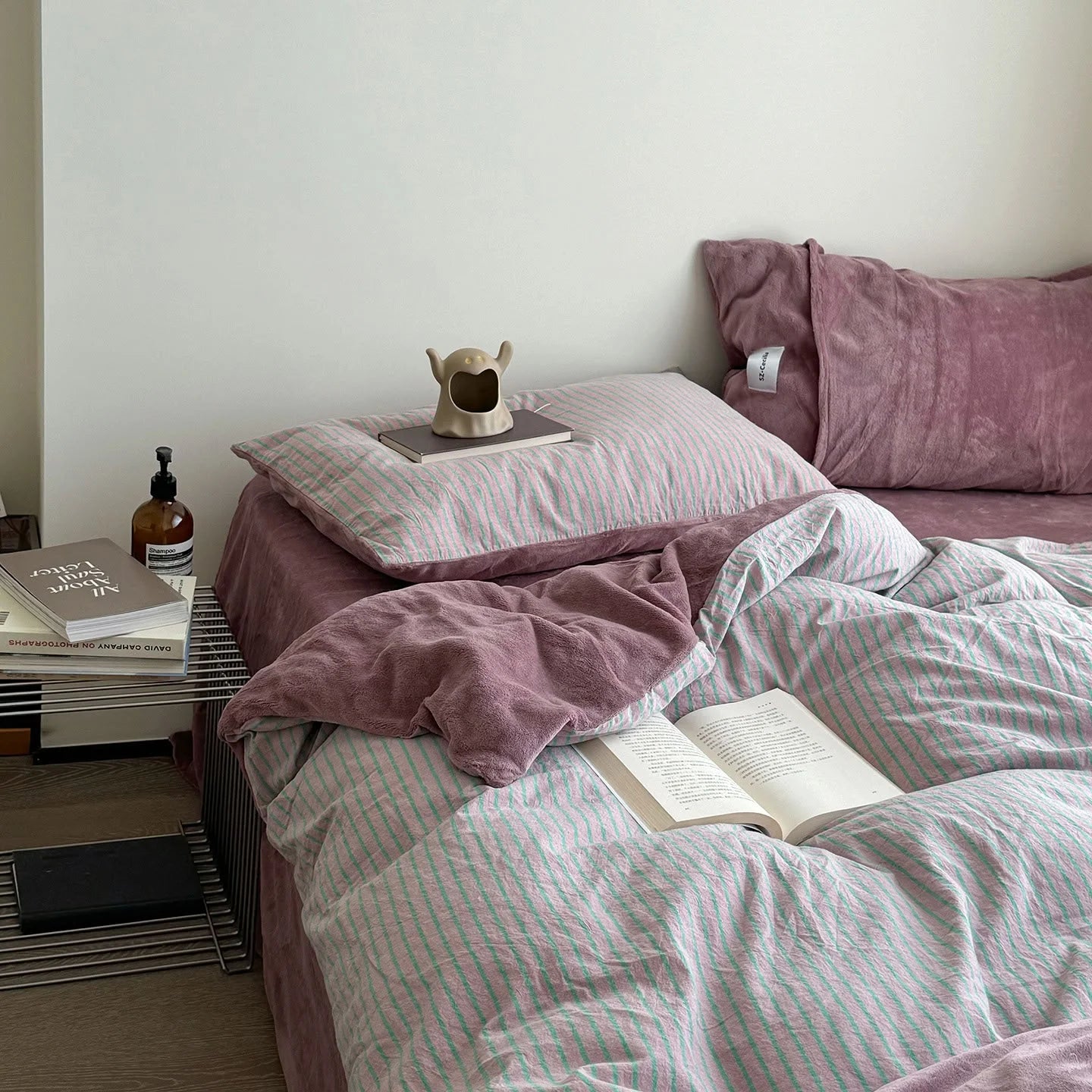 Lifestyle image of the Pink & Mint bedding set with an open book, creating a cozy reading nook vibe.