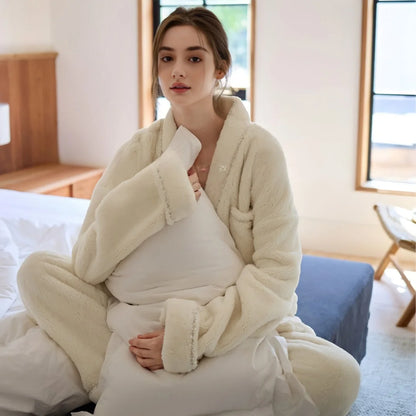 Close-up of a model in the cream fleece pajama set, hugging a white pillow on a bed, showcasing the soft texture - RoomDen.