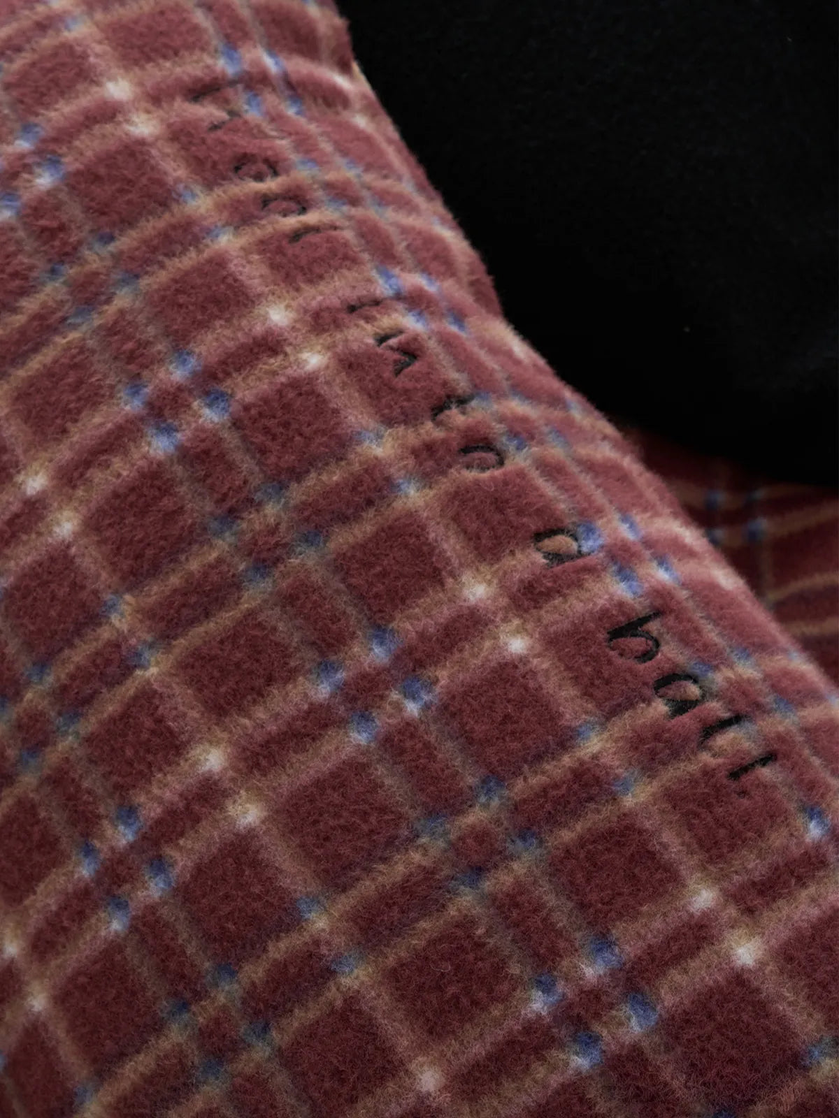 Macro shot highlighting the soft texture and subtle embroidered text on the plush flannel fleece fabric. - RoomDen