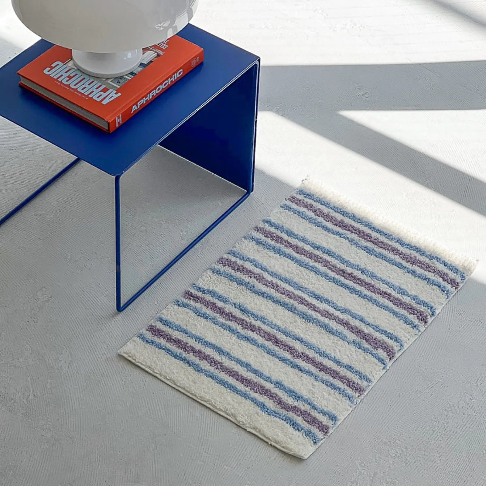 RoomDen - White Accent Rug with Purple and Blue Stripes Next to Blue Side Table