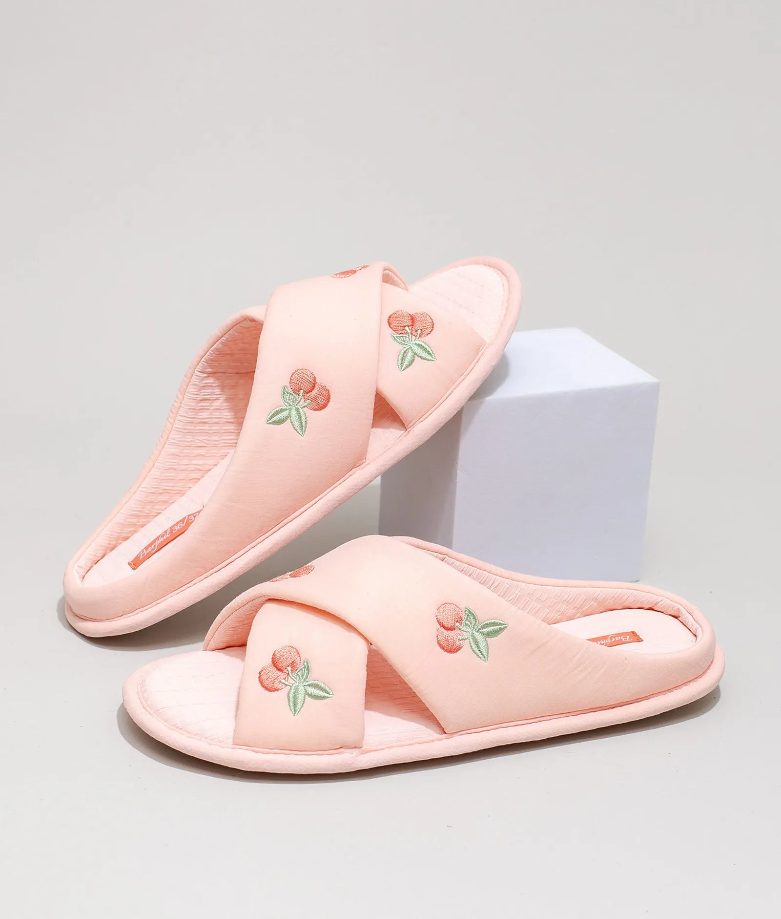 Pink embroidered cherry slippers on display block - RoomDen