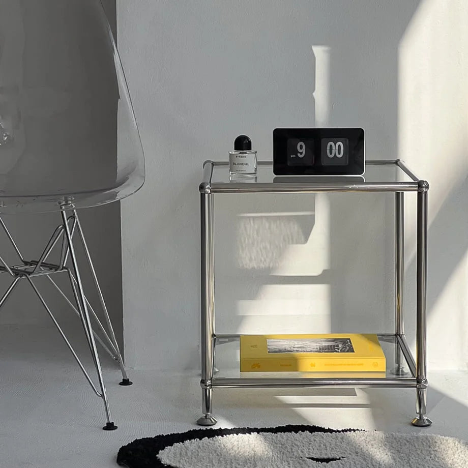 Black and white retro flip clock on a glass and chrome side table, showing 9:00 PM, in a minimalist room. - RoomDen