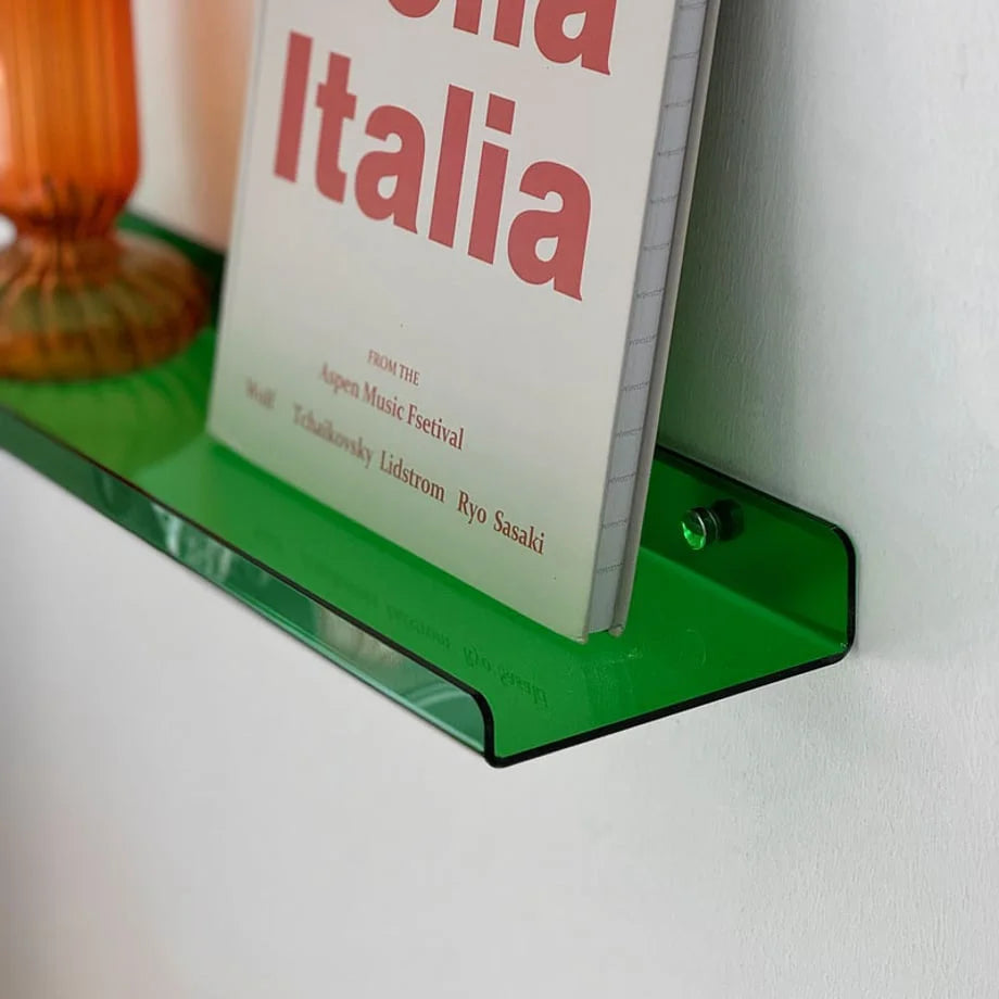 Close-up of the green acrylic floating shelf's edge, showing the material's thickness and glossy finish.