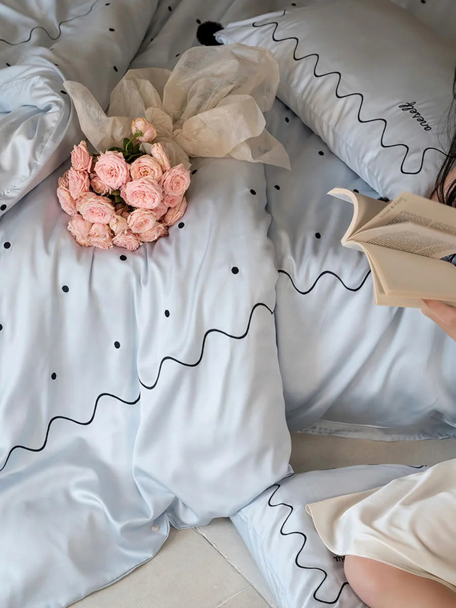 A person reading a book while lying on the Baby Blue & Black silky Tencel bedding set. - RoomDen