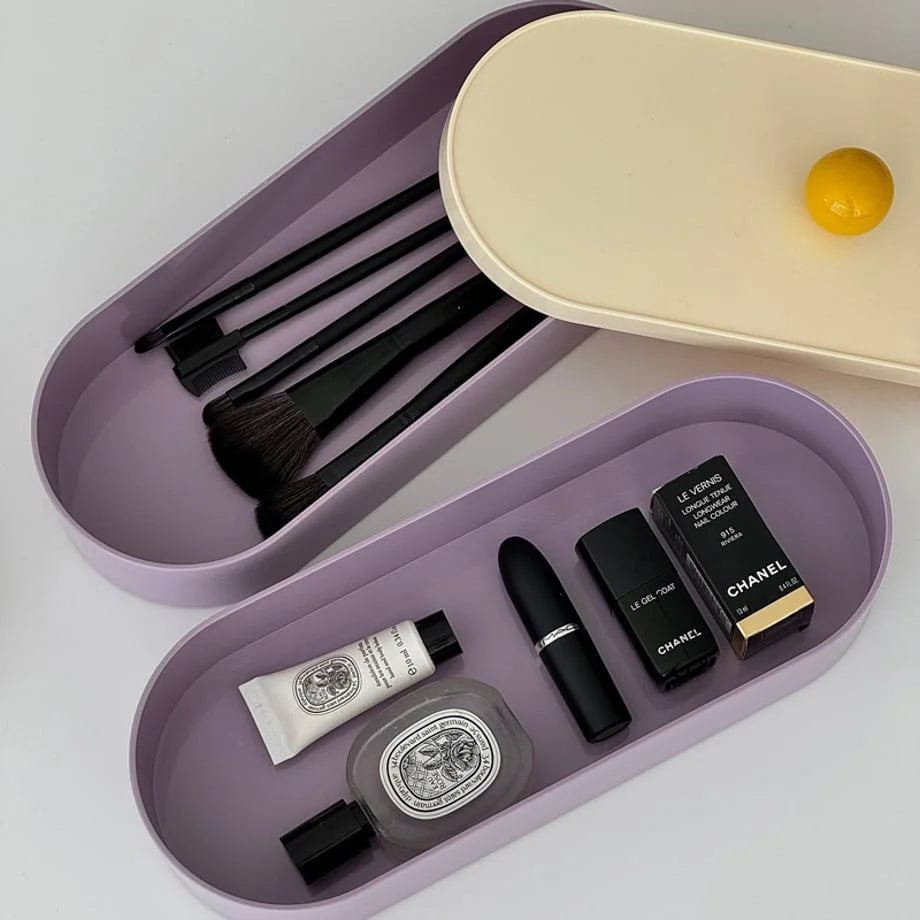 Open view of the two-tier organizer, with makeup brushes in the top tray and cosmetics like lipstick and perfume in the bottom.