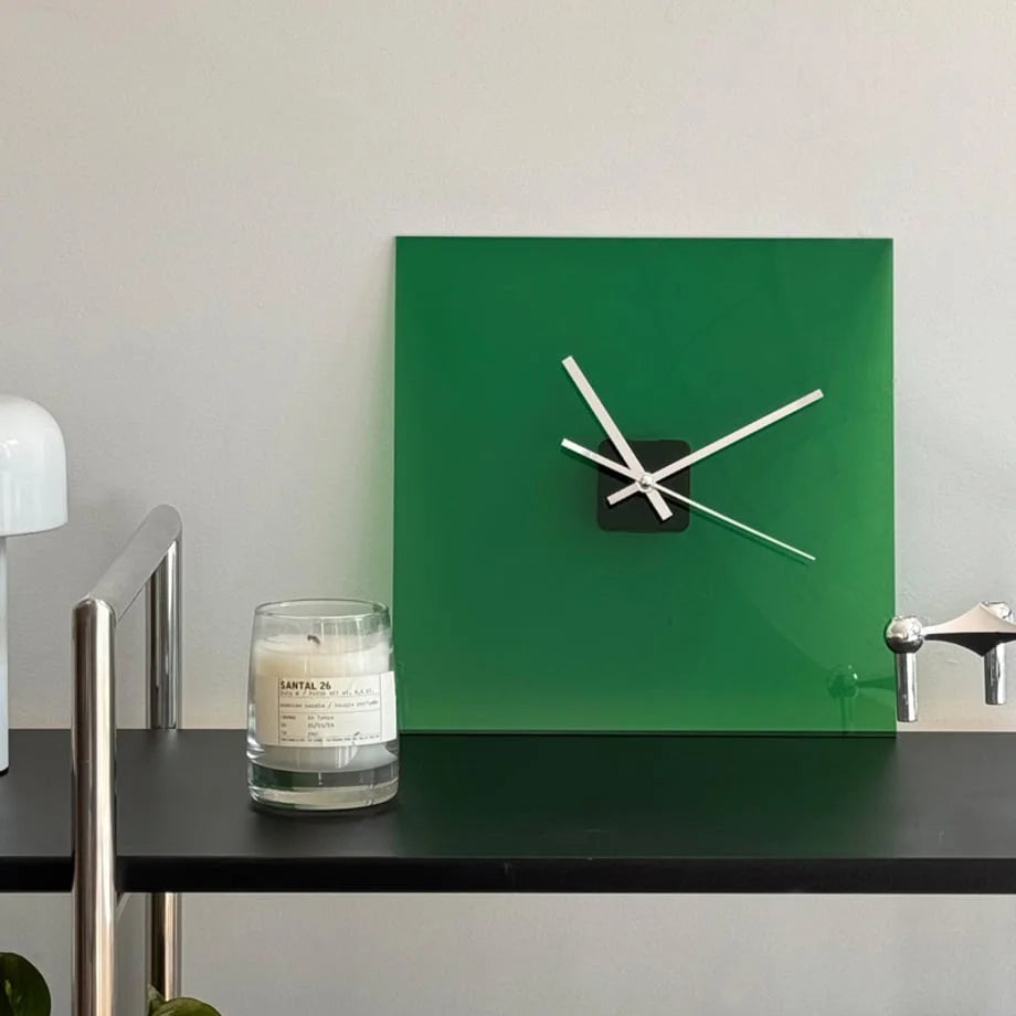 Front view of the Emerald Green acrylic clock next to a Santal 26 candle on a black shelf. - RoomDen