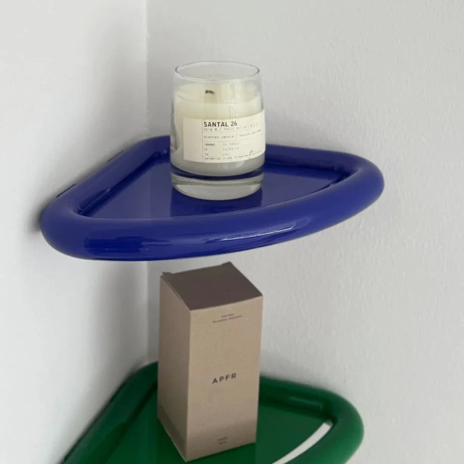 A Santal 26 candle sitting on the glossy blue Chunky Curved Floating Corner Shelf. - RoomDen