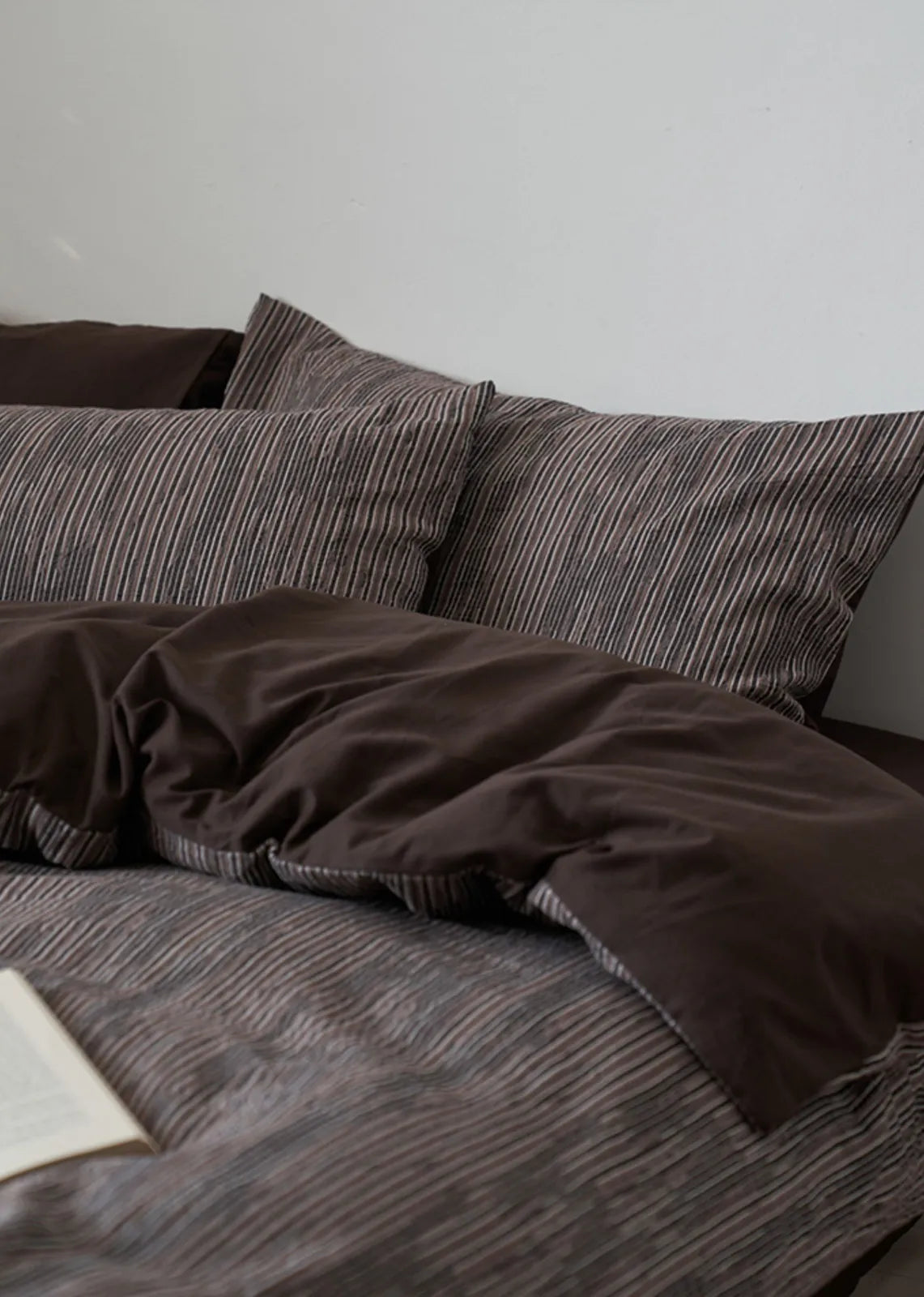 View of the Mocha Brown pinstripe bedding with the solid dark brown duvet reverse folded over.