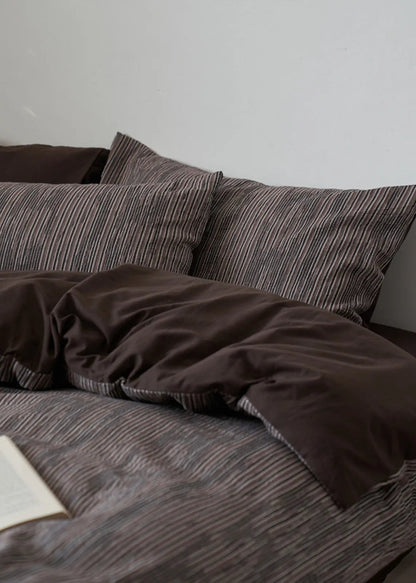 View of the Mocha Brown pinstripe bedding with the solid dark brown duvet reverse folded over.