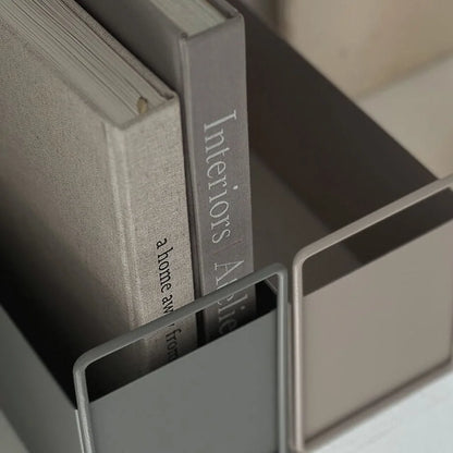 Close-up detail of the matte texture on the metal organizers and the spines of the books they hold. - RoomDen