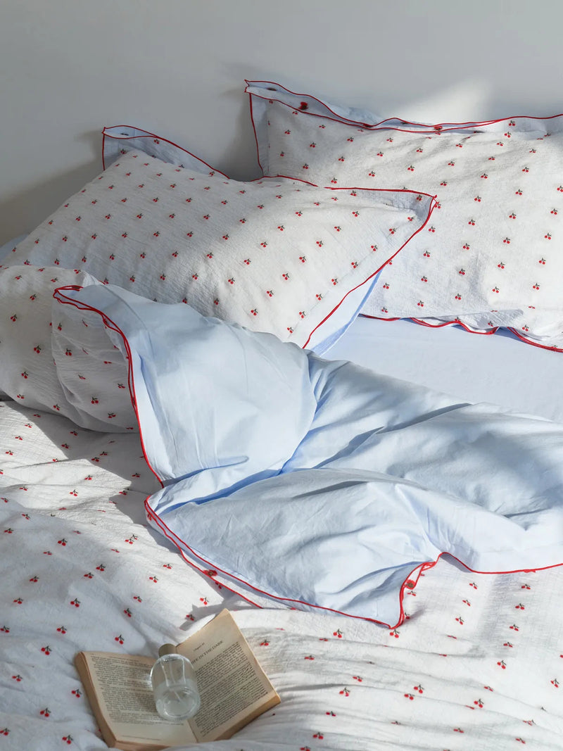 Sunlit view of the Ruffled Cherry Print Duvet Cover Set showing the reversible solid blue side — RoomDen