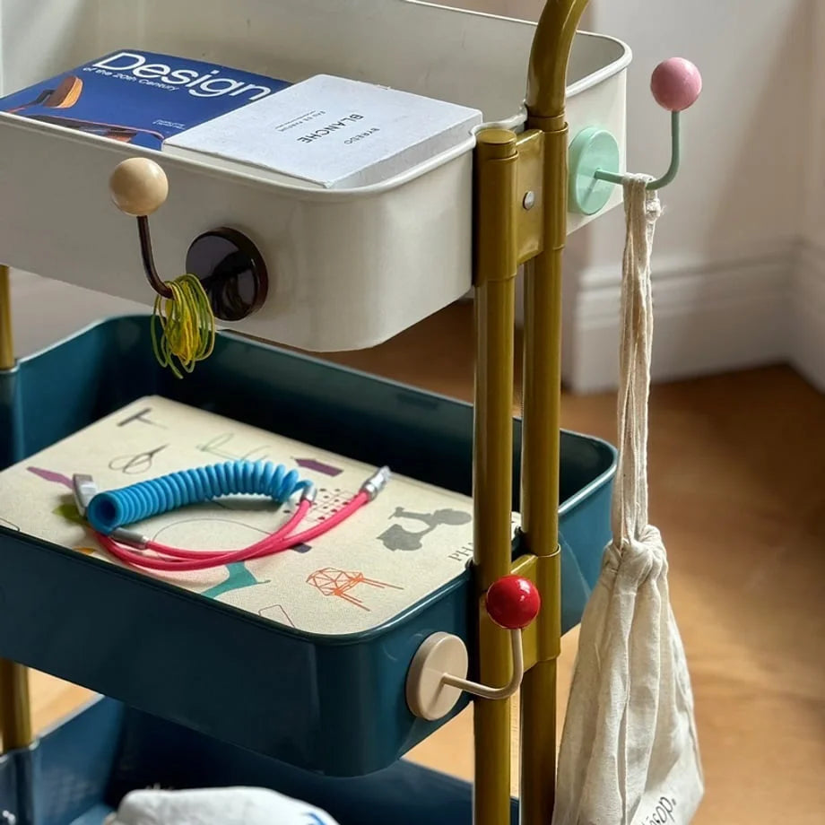 Close-up lifestyle shot of the hooks on a cart holding hair ties, a bag, and books - RoomDen.