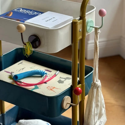 Close-up lifestyle shot of the hooks on a cart holding hair ties, a bag, and books - RoomDen.