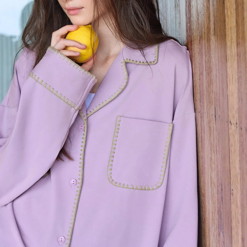 Close-up of the lavender pajama top showing the contrast trim on the pocket and collar - RoomDen