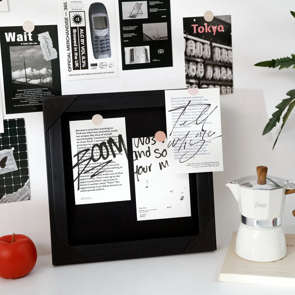 Two cards from the black and white collage kit displayed inside a black shadow box frame on a white desk - RoomDen.