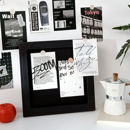 Two cards from the black and white collage kit displayed inside a black shadow box frame on a white desk - RoomDen.