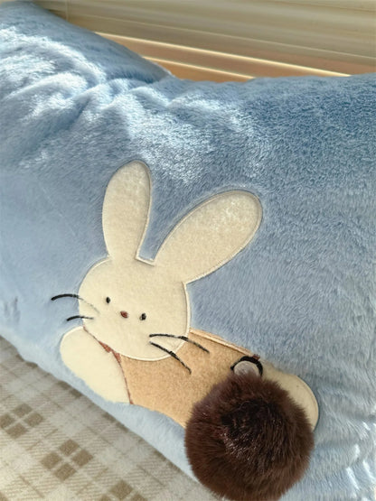Detail shot of the embroidered bunny with a fluffy pom-pom tail on the blue pillowcase.