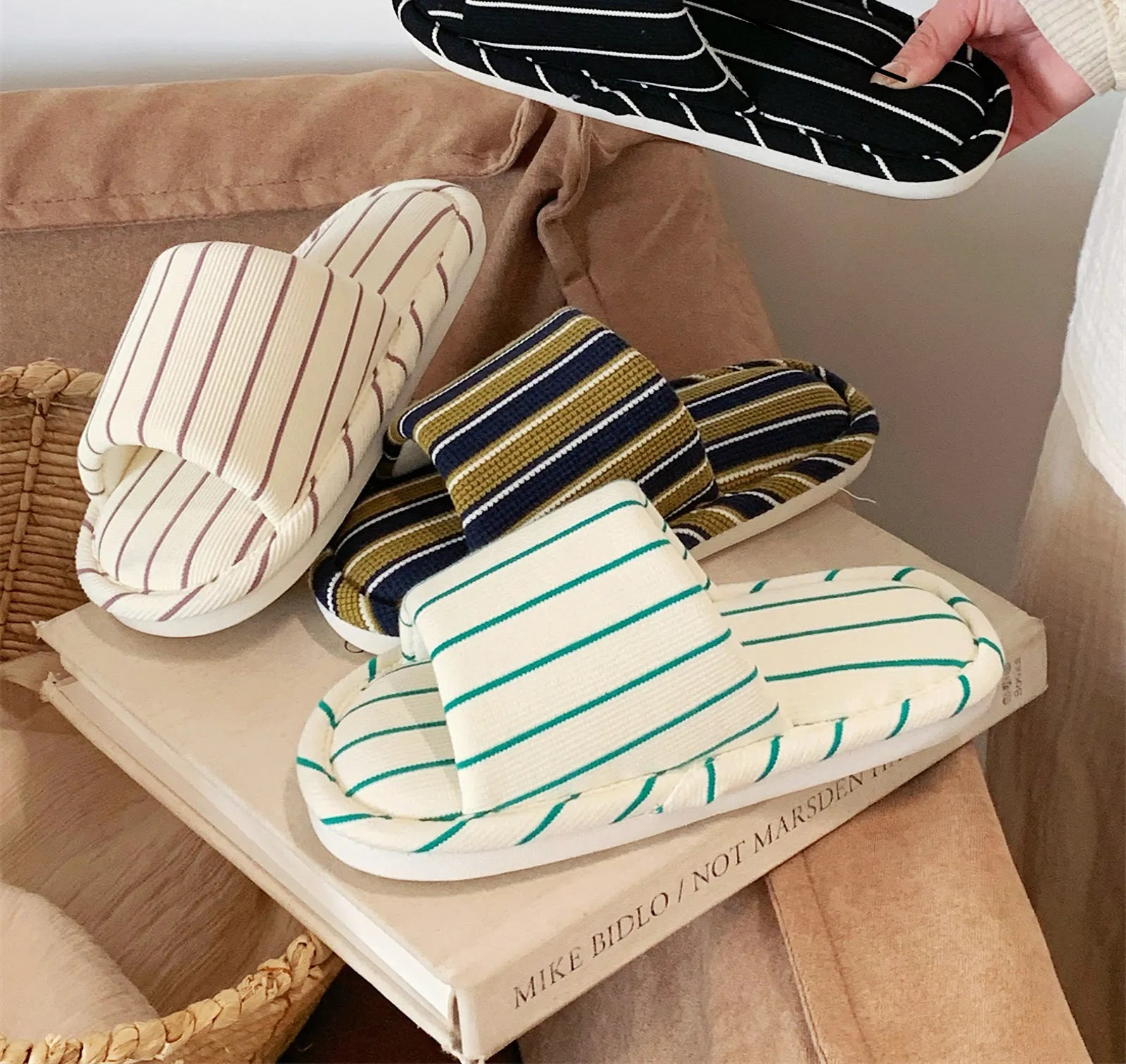 Green and Navy striped cotton slippers placed next to a woven basket and a book, showcasing the Japandi aesthetic.