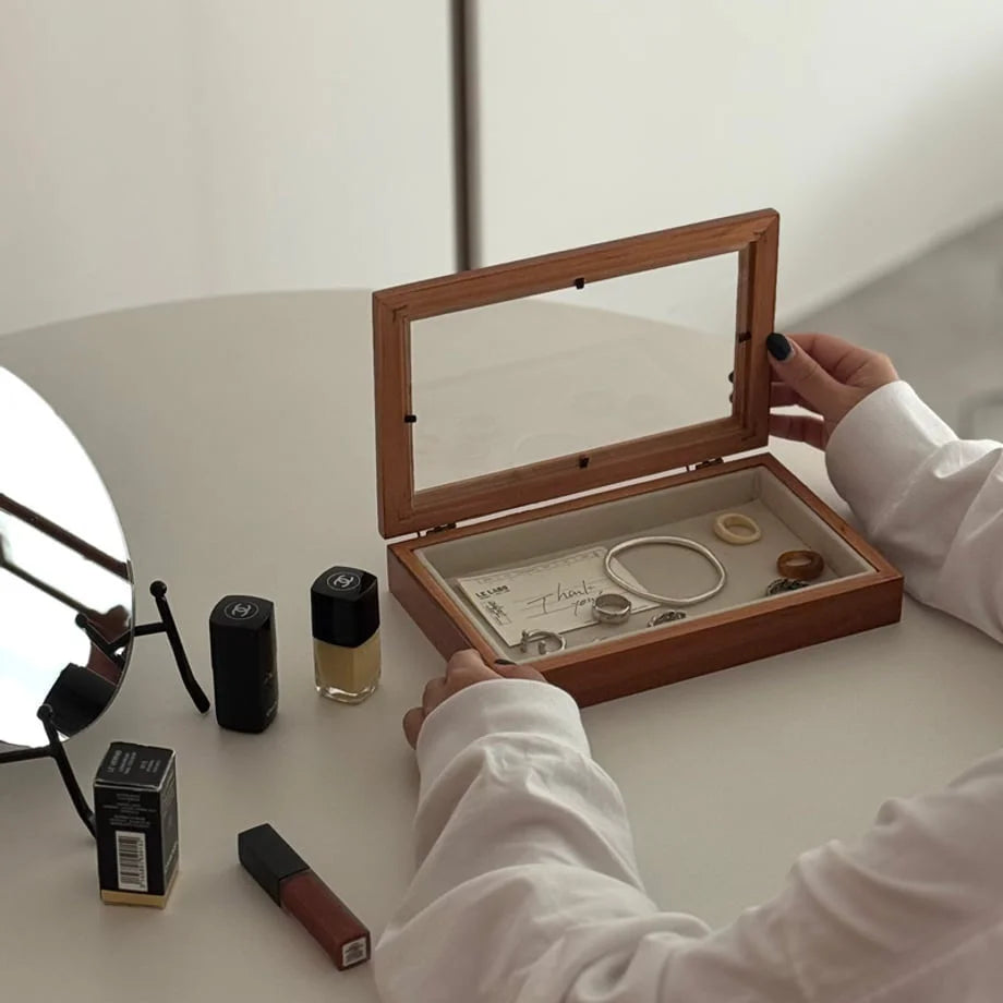 A woman opening a minimalist wood jewelry box with a glass lid on a white table. - RoomDen