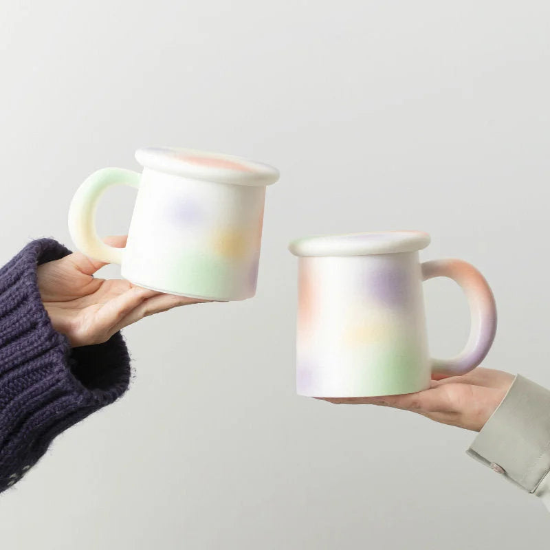 Two hands holding Pastel Sprinkle Frosted Ceramic Mugs against a neutral background - RoomDen.