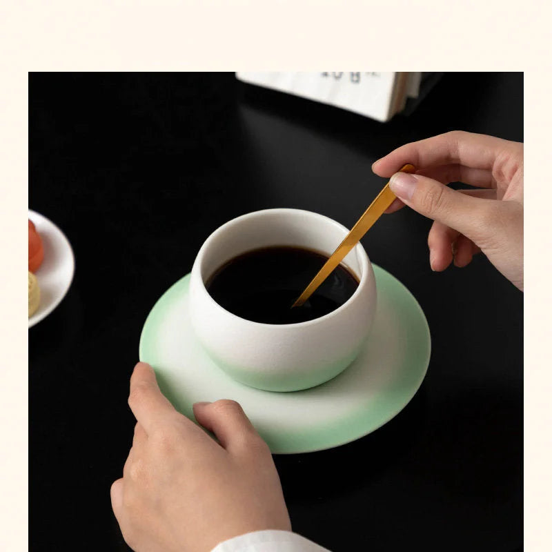 Close-up lifestyle shot of the Mint Green Ombre Ceramic Cup with a golden spoon. - RoomDen