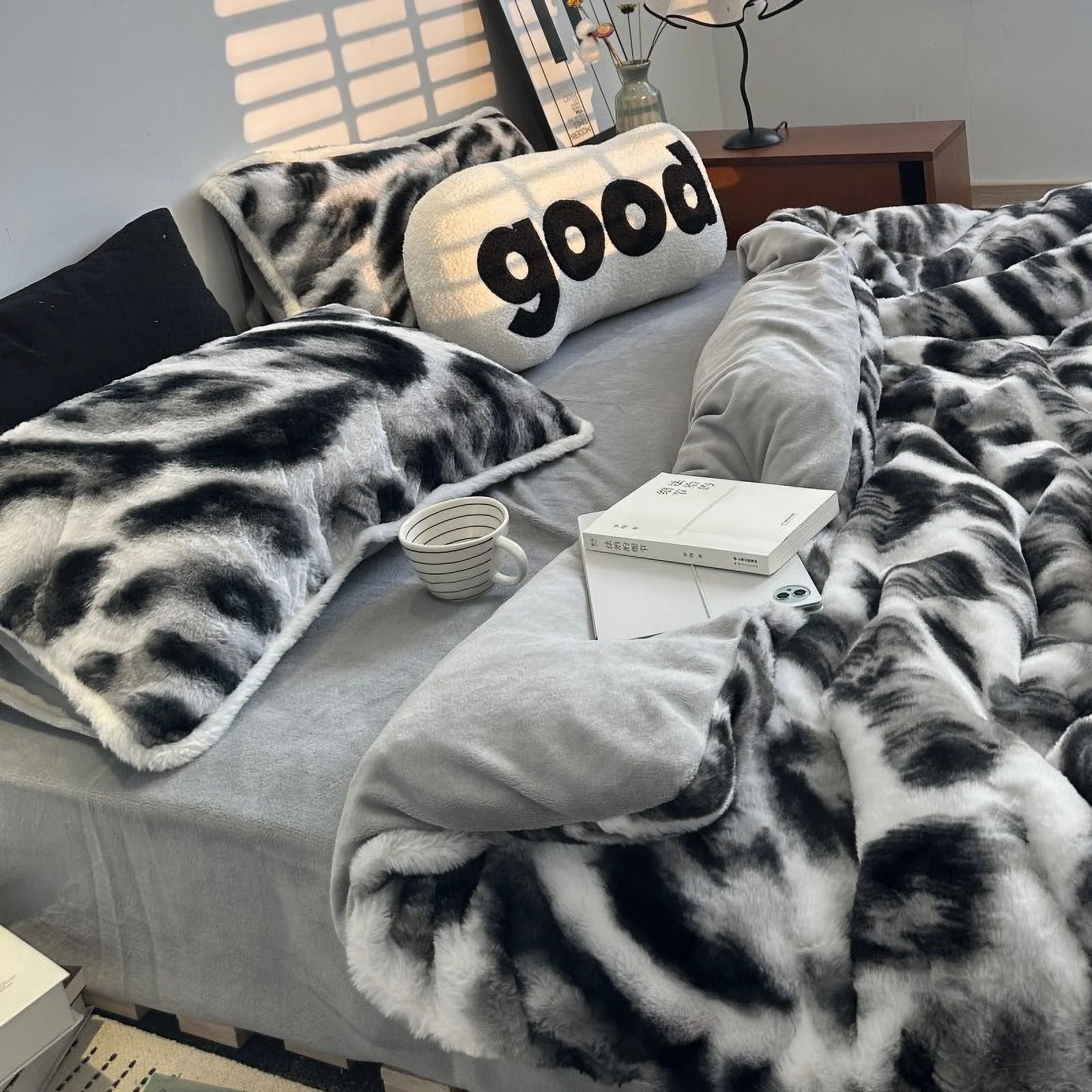 Angled view of the bed with the black and white abstract bedding, with sunlight from blinds creating a cozy atmosphere. - RoomDen