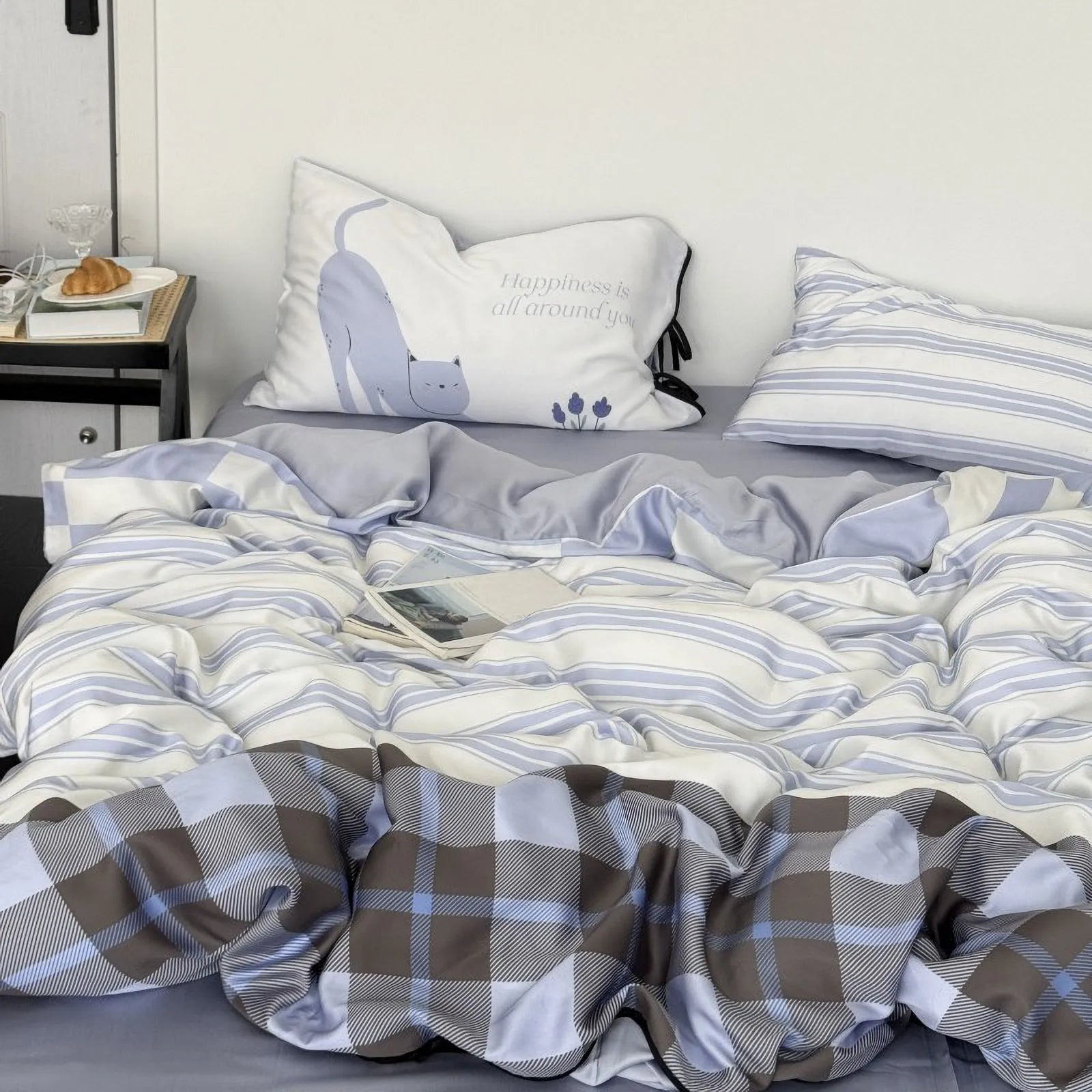 Lifestyle image showing the reversible plaid side of the duvet cover mixed with the striped pillows and cat pillow. - RoomDen