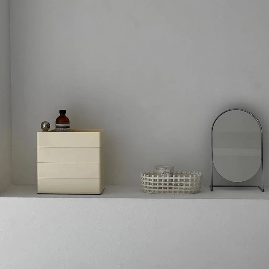 Sleek Minimalist ABS Rotating Makeup Organizer in Cream Beige, closed on a white shelf next to a mirror.