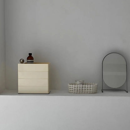 Sleek Minimalist ABS Rotating Makeup Organizer in Cream Beige, closed on a white shelf next to a mirror.