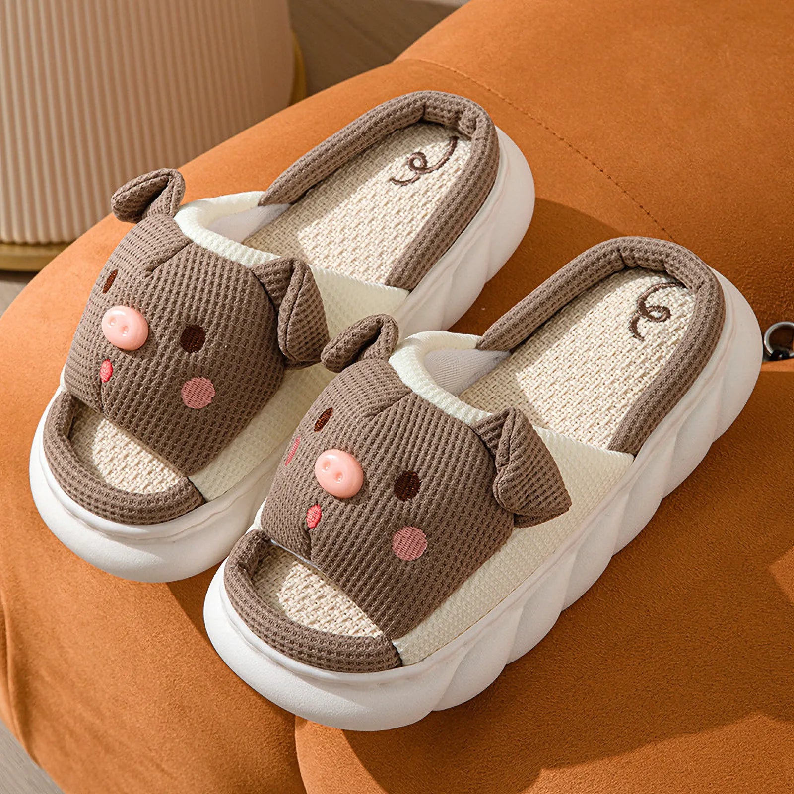 Pair of Brown Waffle Textured Embroidered Pig Linen House Slippers on an orange surface - RoomDen