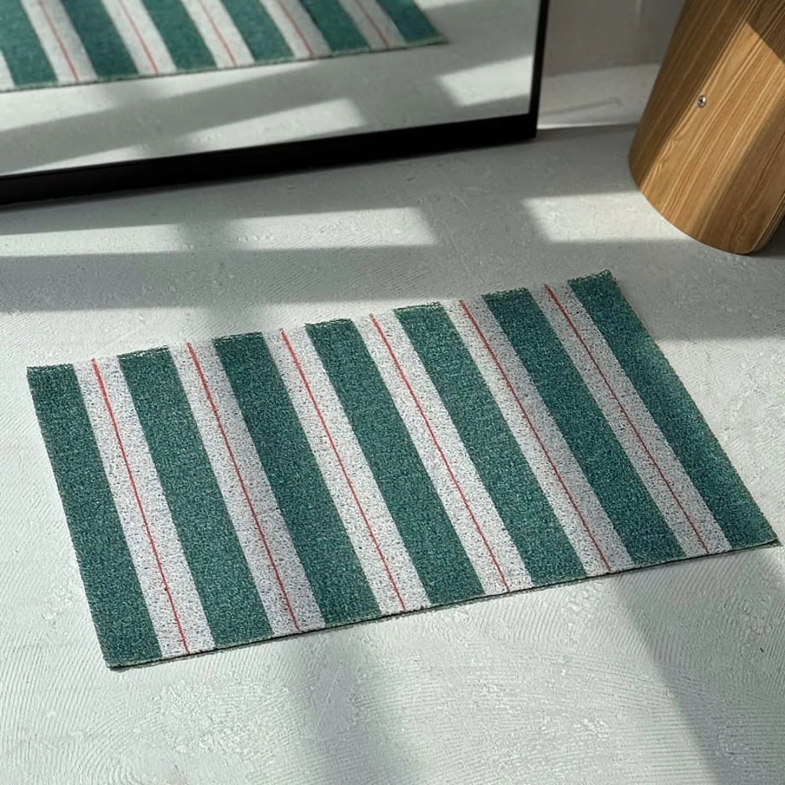 Top down view of green and white striped doormat showing linear pattern - RoomDen
