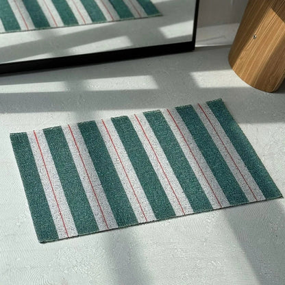 Top down view of green and white striped doormat showing linear pattern - RoomDen
