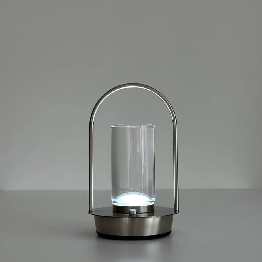 The Minimalist Arch Metal Portable Table Lamp turned on with a bright white light. - RoomDen